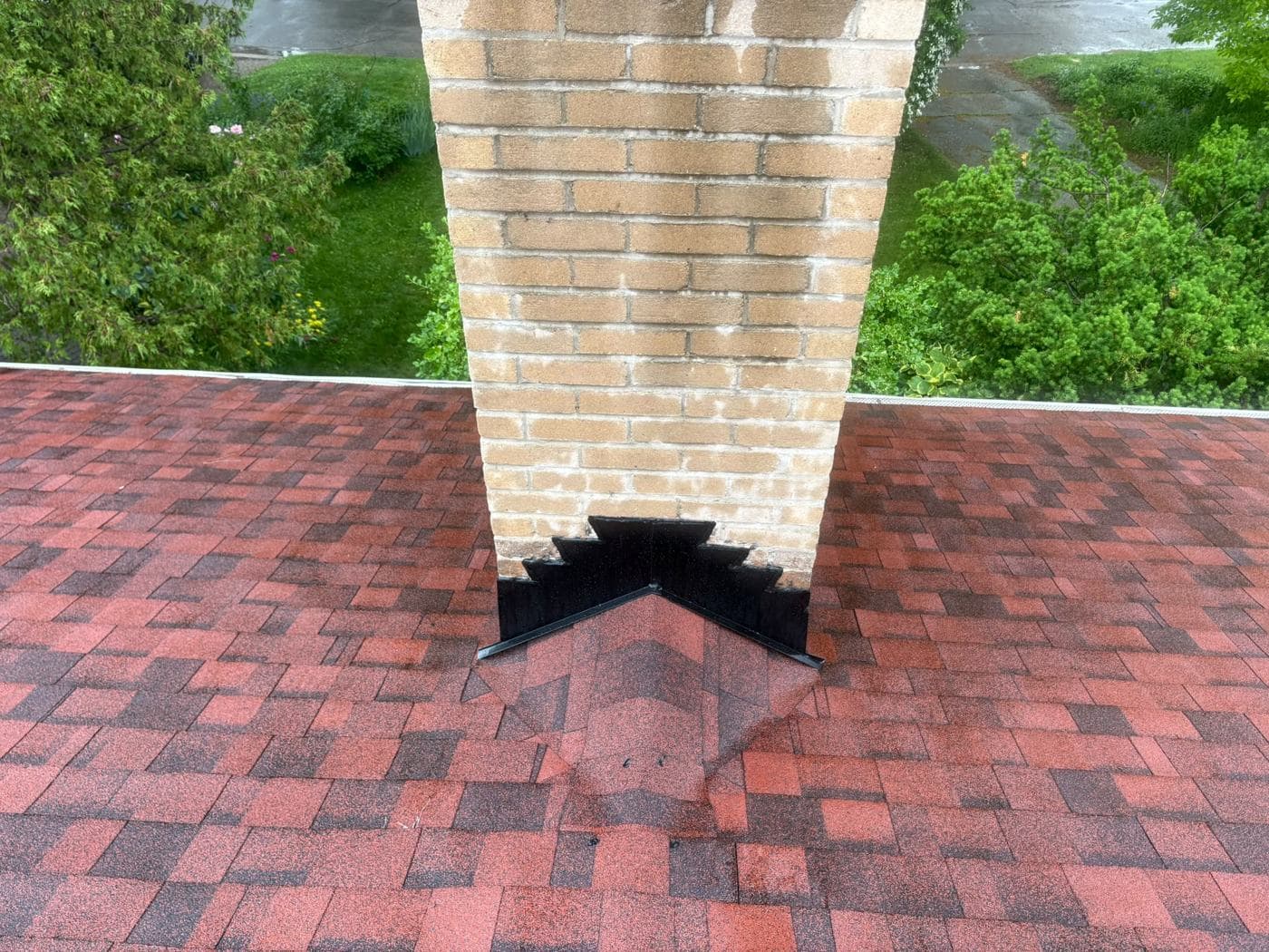 New step flashing around a chimney on a red shingle roof