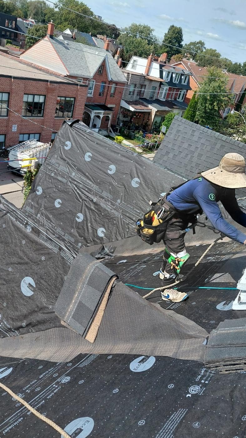 Roofer laying underlayment on a steep roof